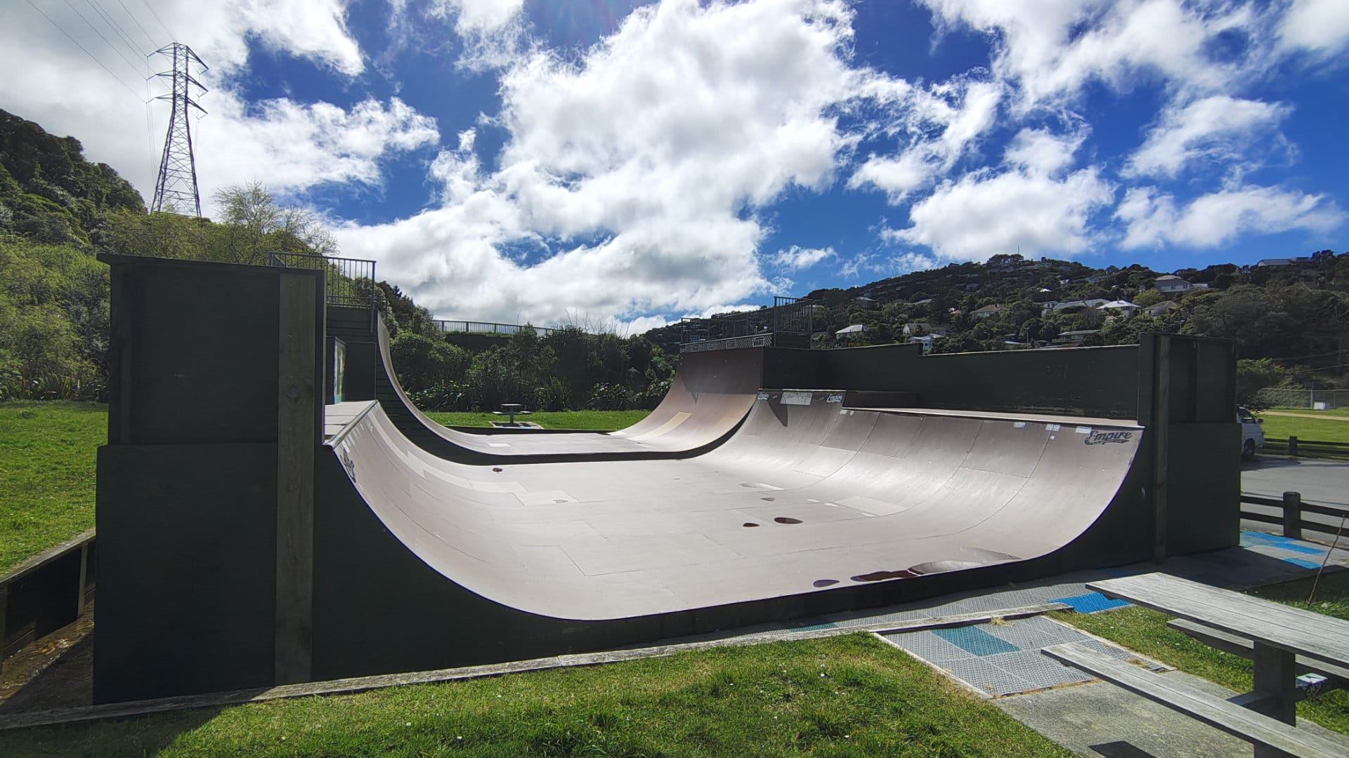 Empty half-pipe skate ramp beneath a cloudy blue sky