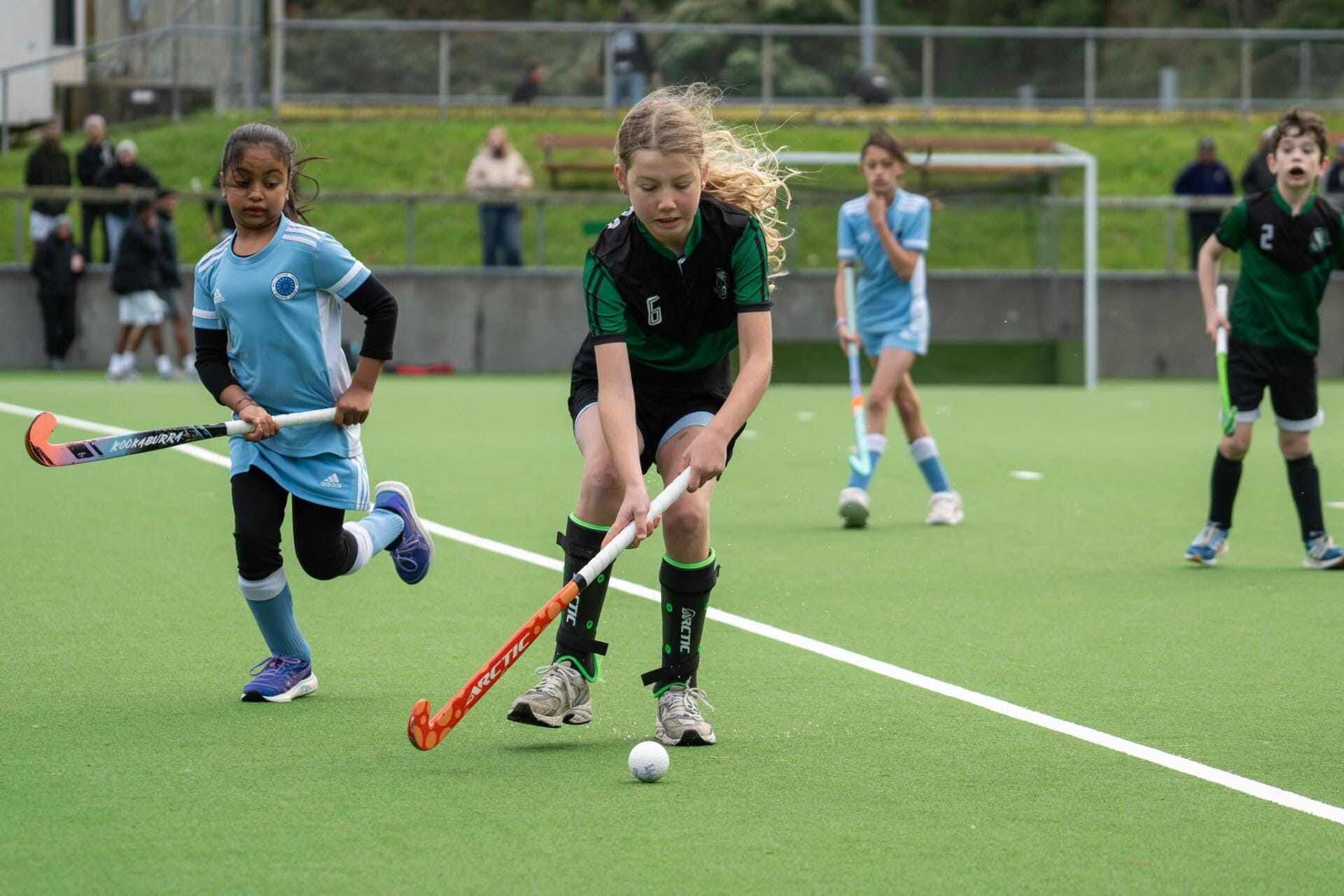 Children playing field hockey on artificial turf