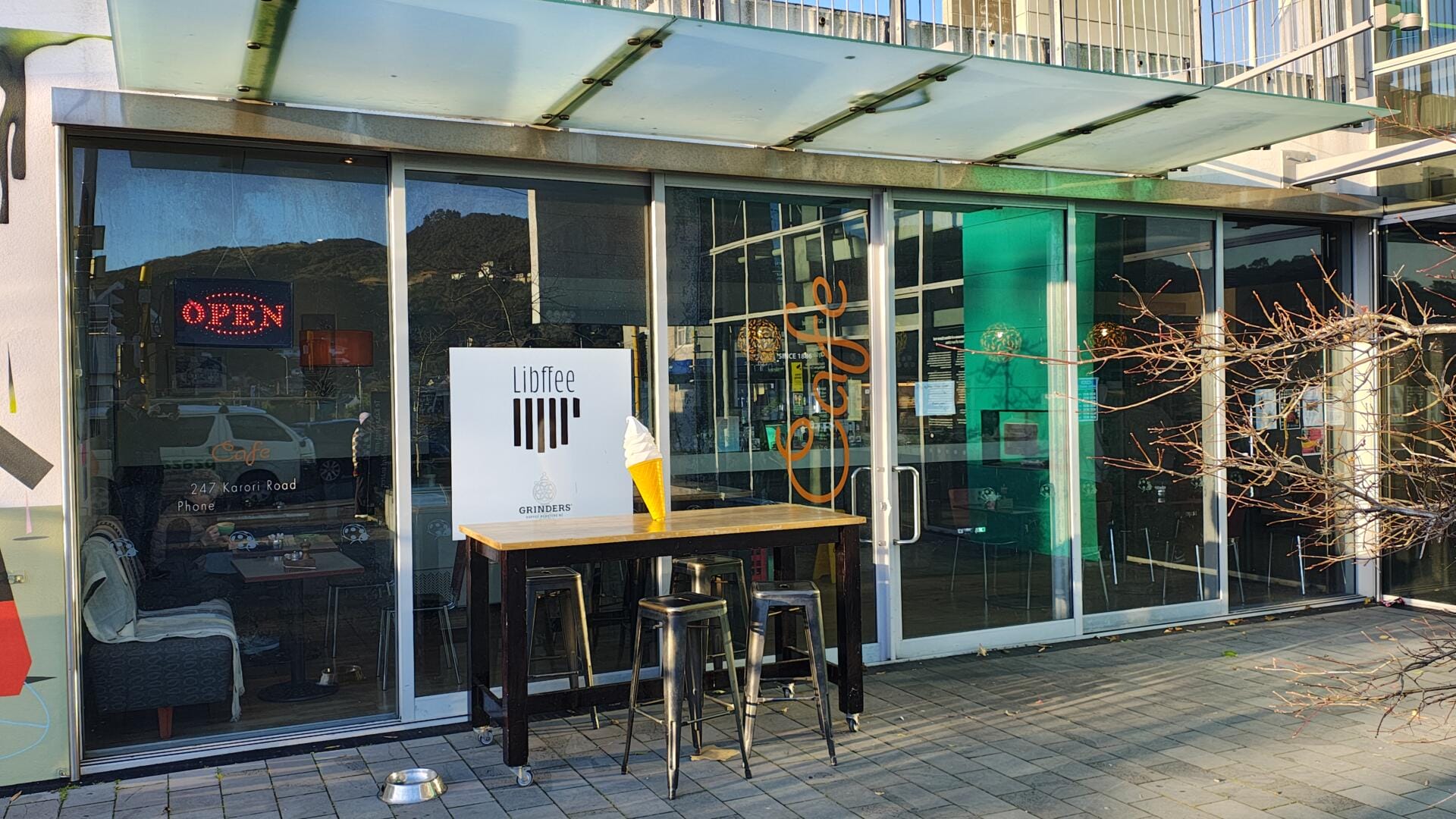 Modern café storefront with outdoor table and stools