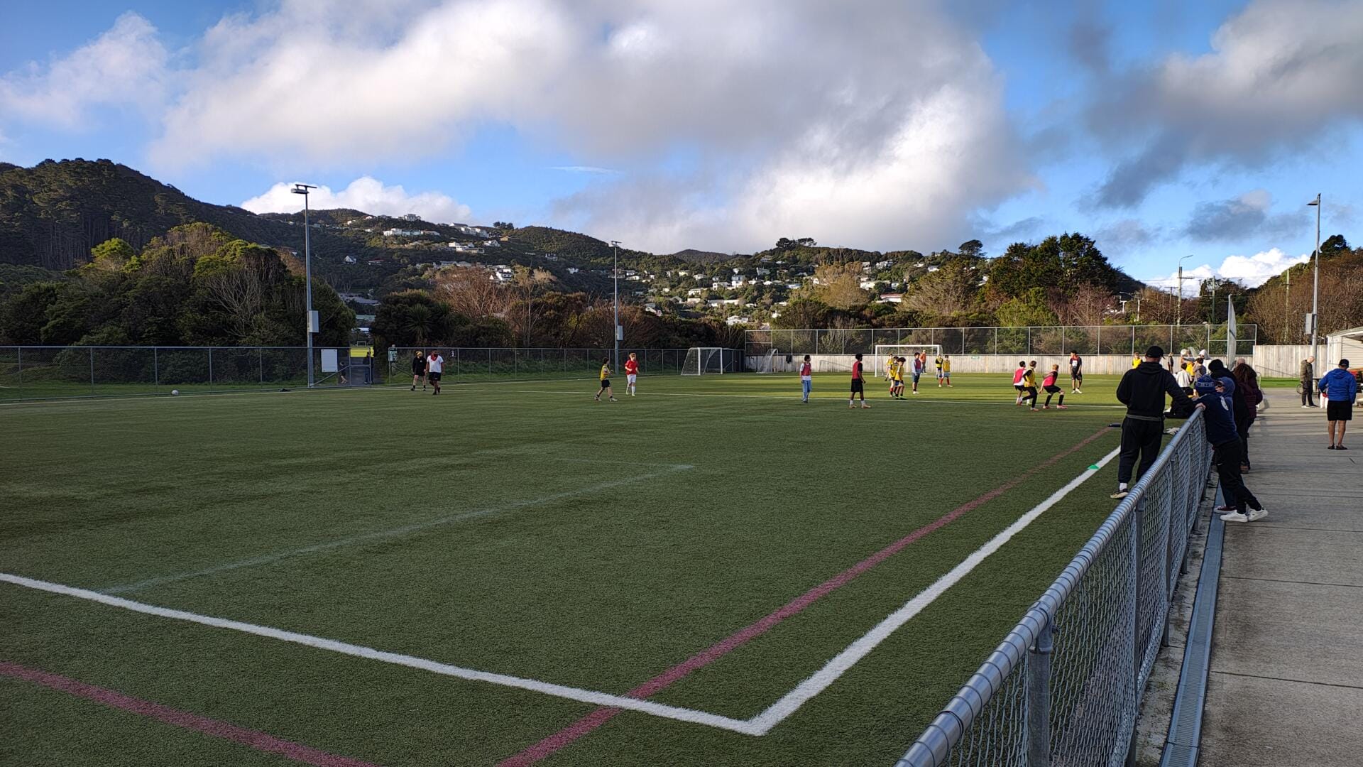 Community football match on turf field with hills
