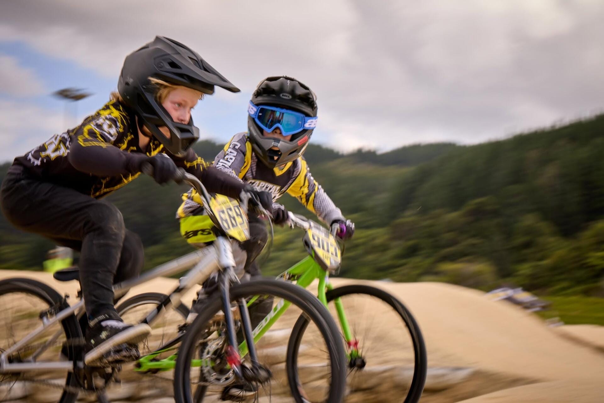 Two kids racing BMX bikes on dirt track