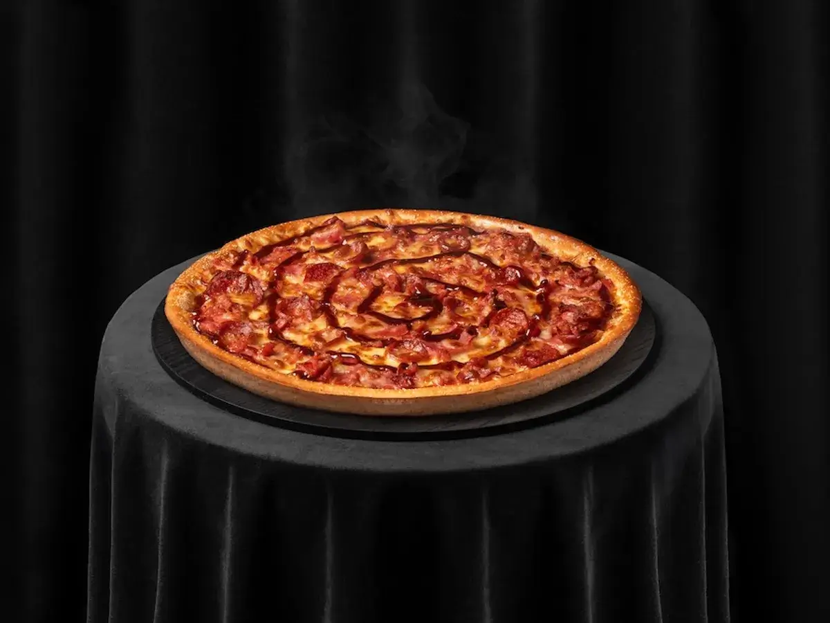 Steaming meat pizza on black table