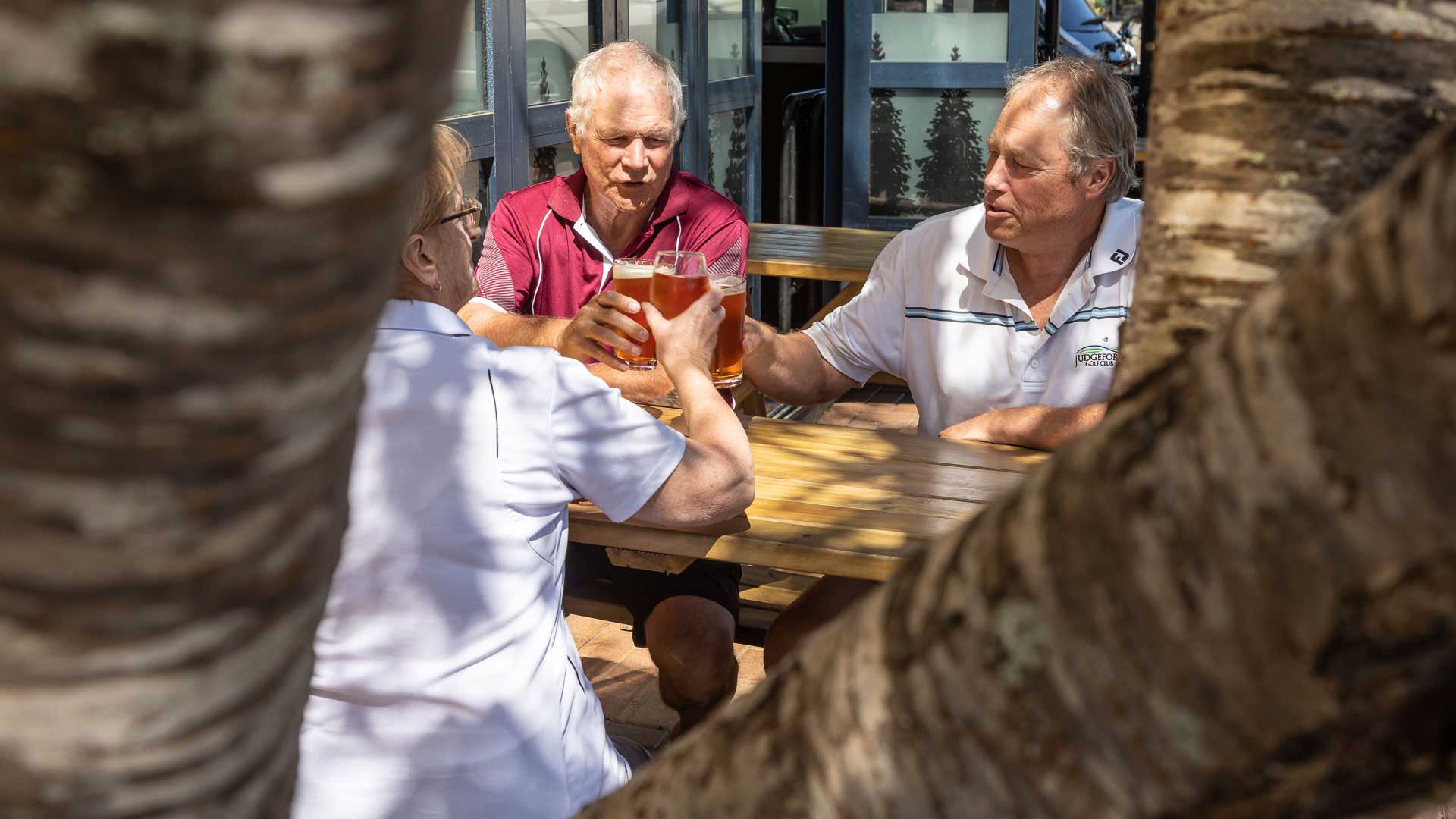 Friends sharing drinks at an outdoor table in Karori