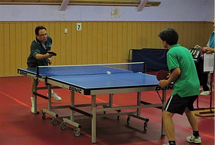 Two men playing table tennis indoors