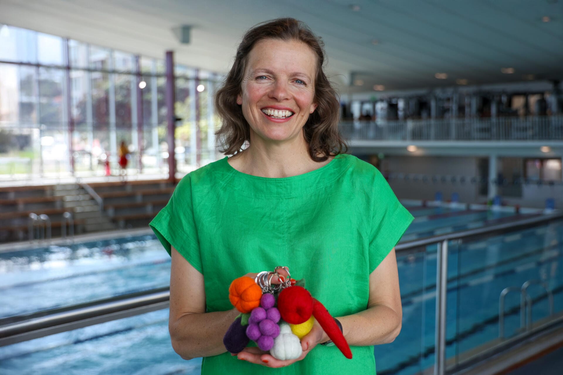 Woman holding colourful felt keyrings by indoor pool