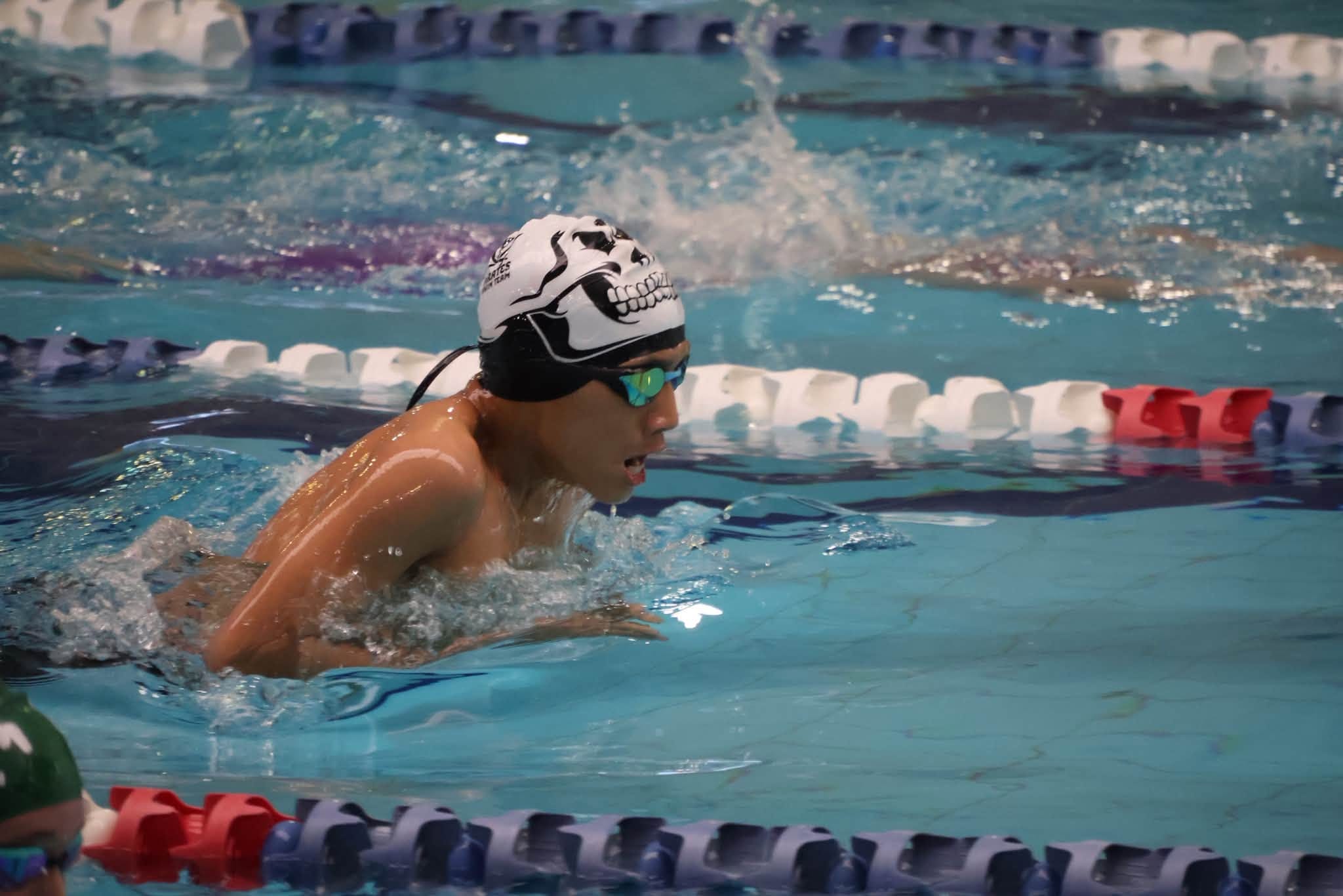 Competitive swimmer performing breaststroke in indoor pool