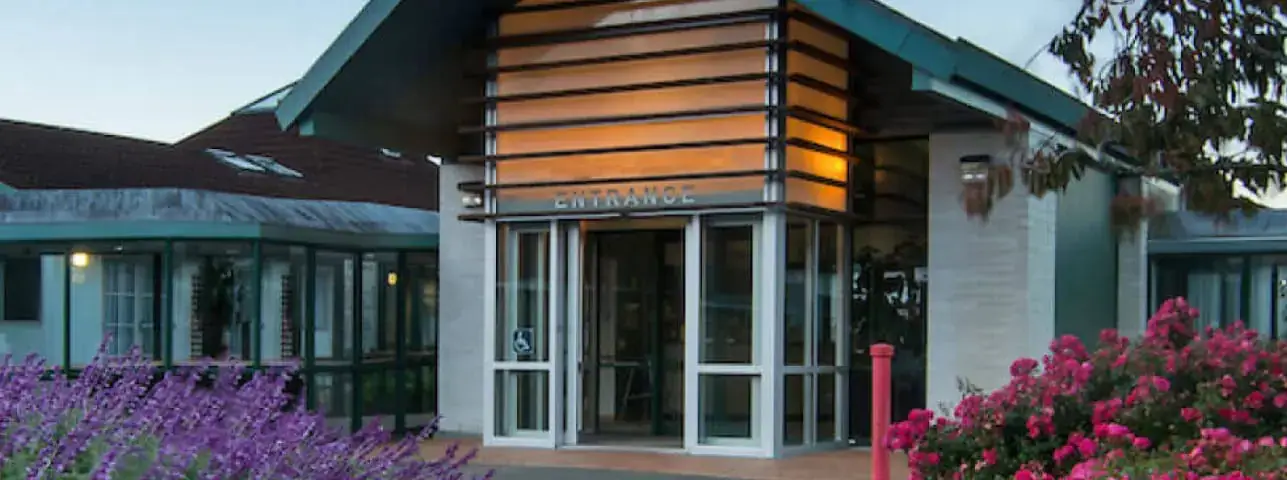 Modern building entrance with glass doors and flowers