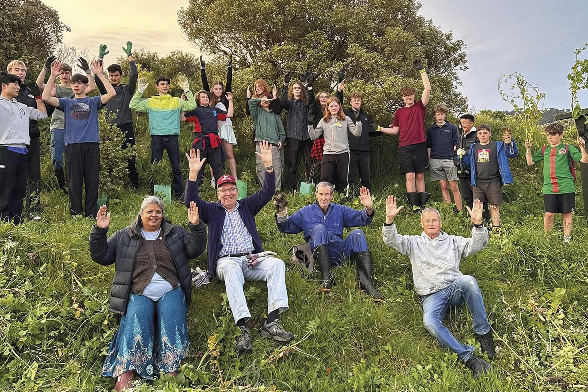 Community group planting trees on grassy hillside