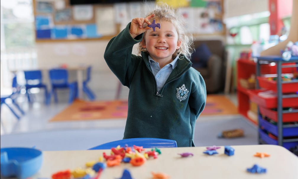 Smiling child holding toy plane in classroom