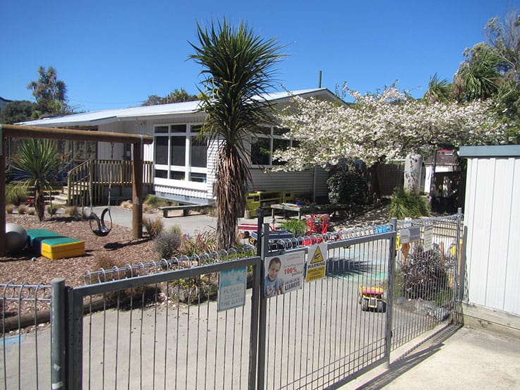 Childcare playground with fence and classroom building